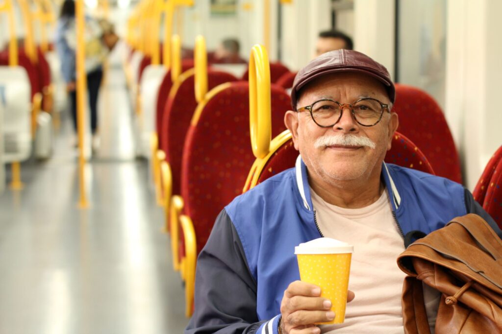 Senior man drinks a coffee while sitting on the bus.