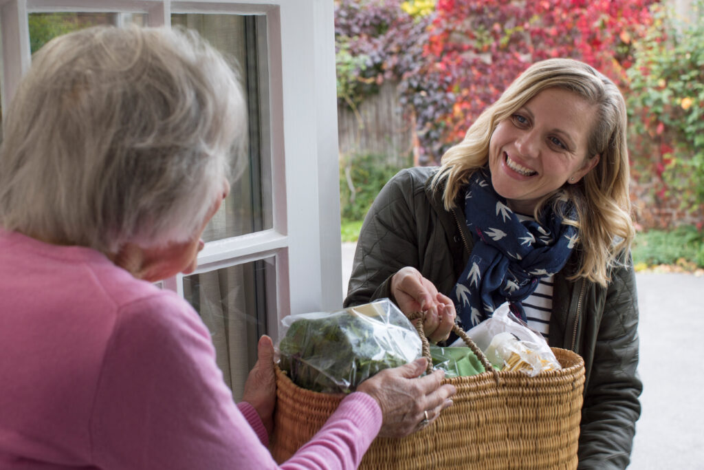 a woman has a basket of groceries handed to her