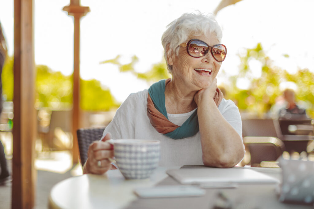 senior woman sits on a patio with a drink