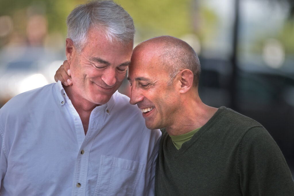 two men lean lovingly