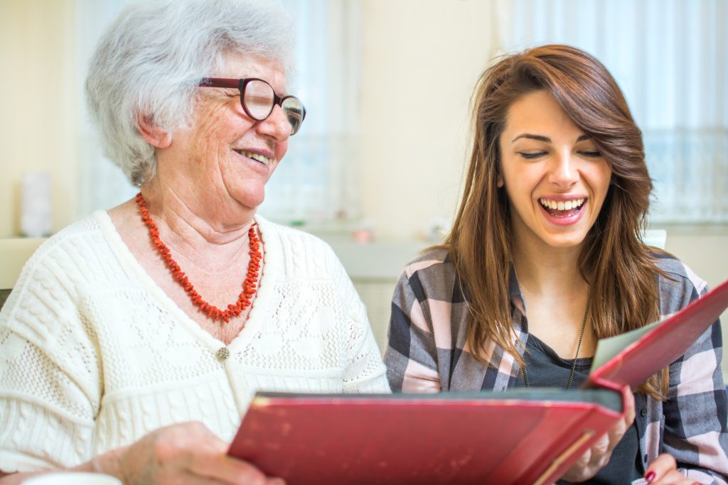 Older and younger woman looking at old photos at photo album.